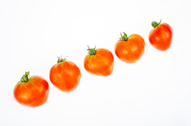 Red tomatoes in shape of heart on white background. Studio Photo.