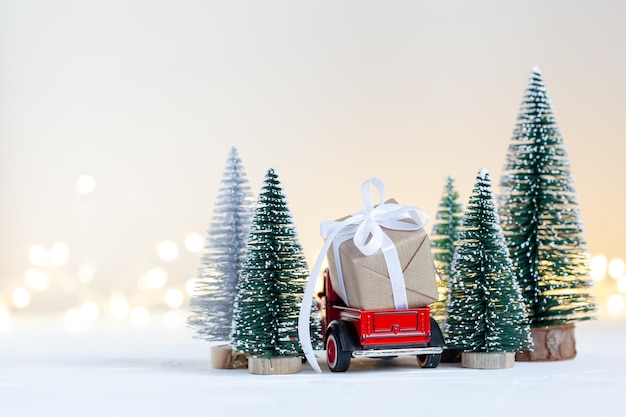 Red toy car truck carrying of Christmas gift boxes aginst netural background Holiday greeting card Back view