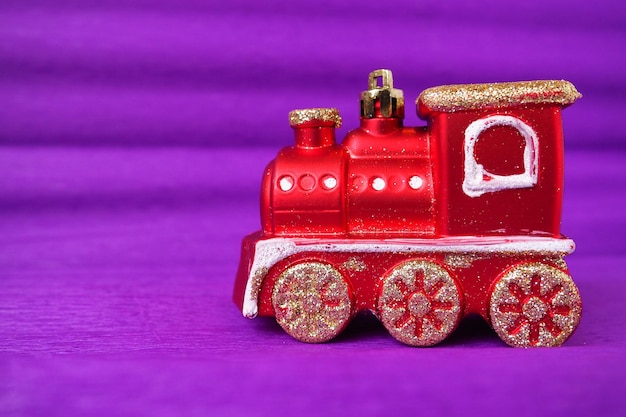 Red toy train locomotive on a purple and lilac gradient background New Year or Christmas card Icicles and snow on a train Free space for text Copy space Festive background