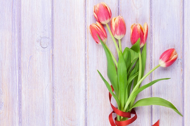 Red tulips over purple wooden table