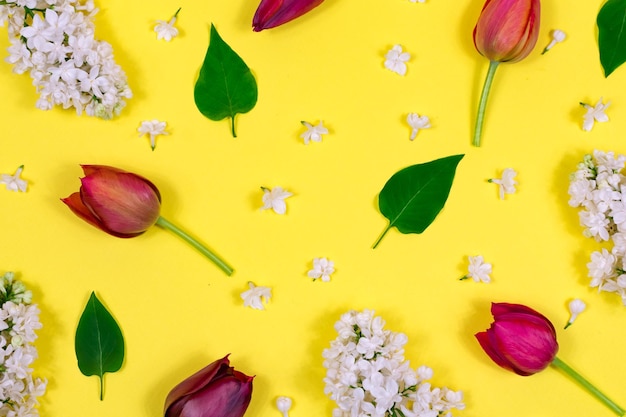 Red tulips white lilac and green leaves on a yellow background View from above Blank for a postcard Mother's Day Valentine's Day Birthday celebration concept Spring Top view greeting card