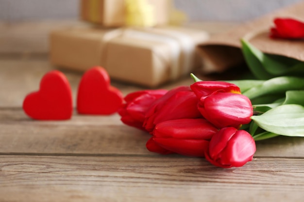 Red tulips with decorative hearts on a wooden table close up