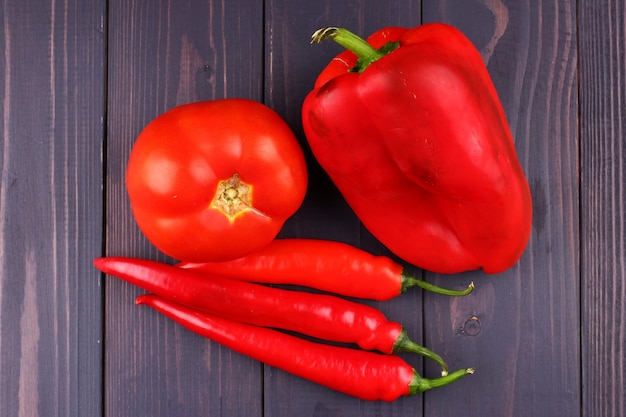 Red vegetables, peppers and tomatoes on a wooden surface