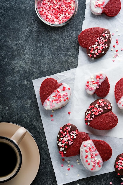 Red velvet or brownie cookies on heart shaped in chocolate icing with red roses on black background Dessert idea for Valentines Day Mothers or Womens Day Homemade dessert Cake for Valentines Day