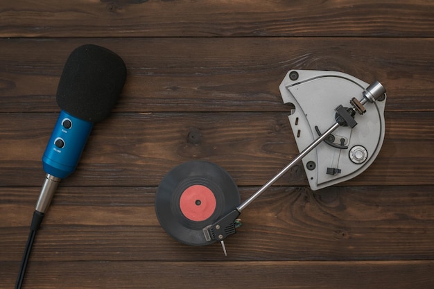 Red vinyl disc in vintage turntables and microphone on wooden background. Retro technique for playing music.