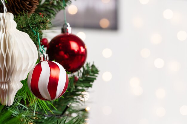 Red and white baubles hanging from a Christmas tree close up