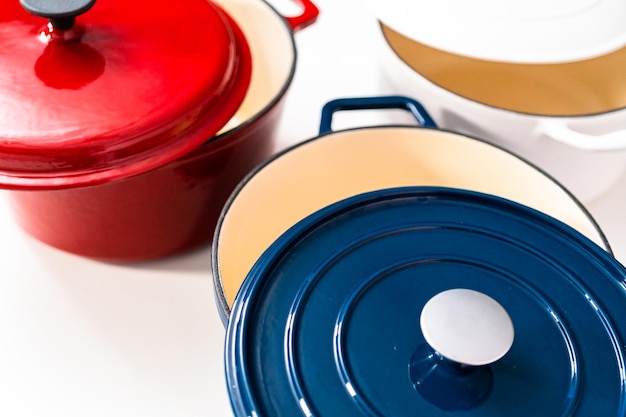 Red, white and blue enameled cast iron covered round dutch ovens on a whjite background.