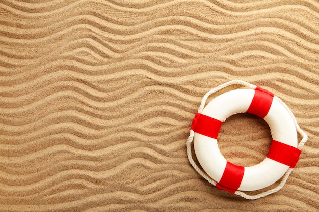 Red-white lifebuoy on sand. Summer concept with copy space