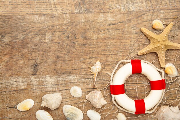 Red-white lifebuoy with sand and seashells on brown