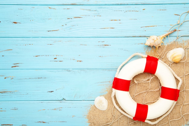 Red-white lifebuoy with seashells on a wooden background