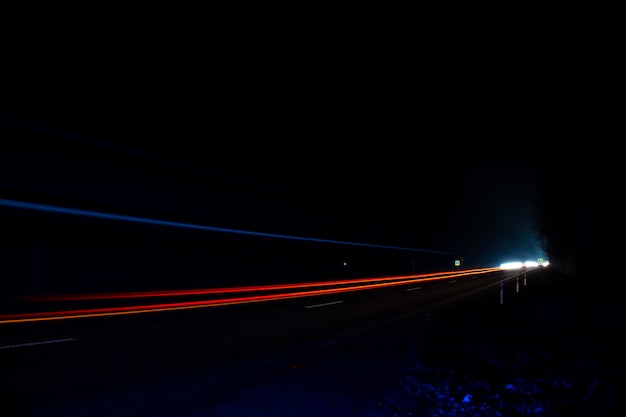 Red and white lights from passing cars. Night highway.