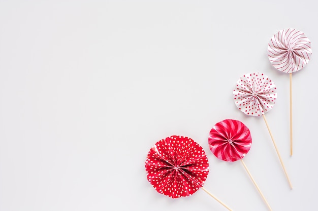 Red and white paper fan with wooden stick on white background for party decoration