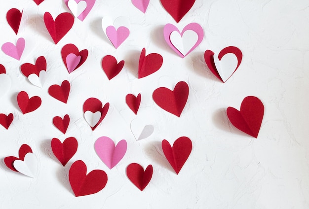 Red white and pink paper hearts cut out of paper for decorating on Valentines Day on a table