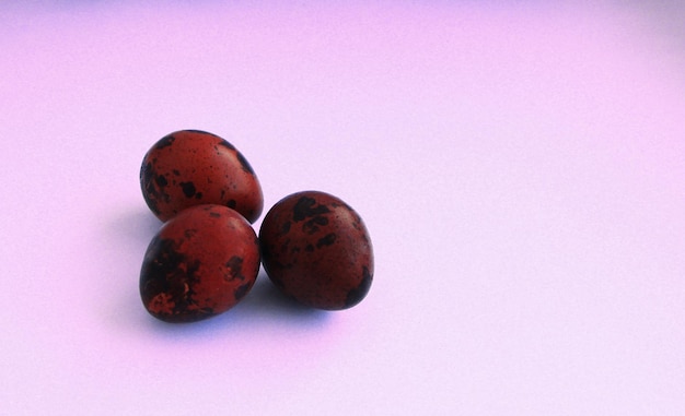 Red and white quail eggs on a pink background