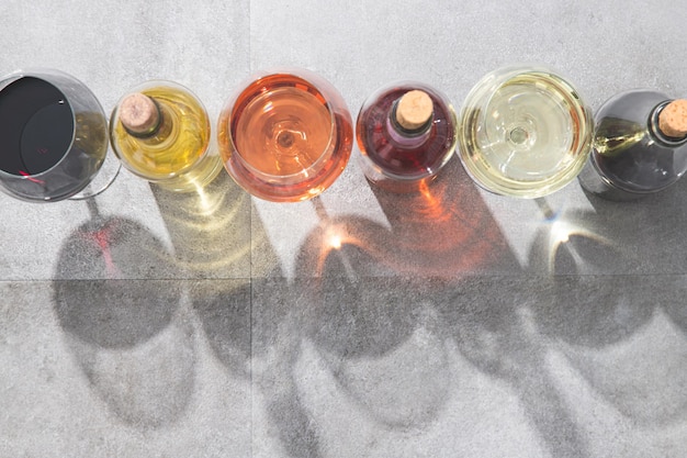 Red white and rose wine in wine glasses and bottles with deep shadows on concrete background with copy space Wines concept