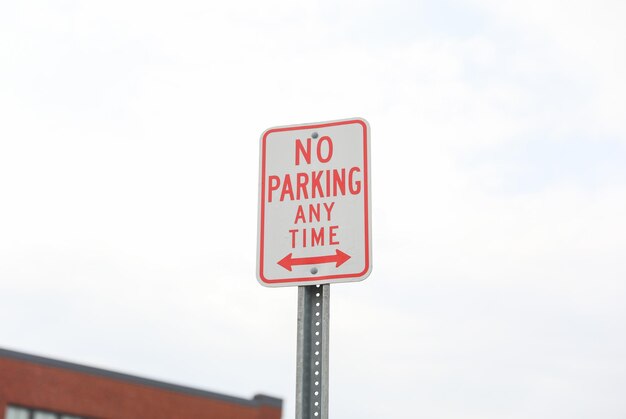 A red and white sign that says no parking any time any time.