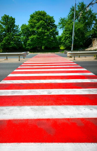 a red and white striped pedestrian crossing with a red and white striped crosswalk