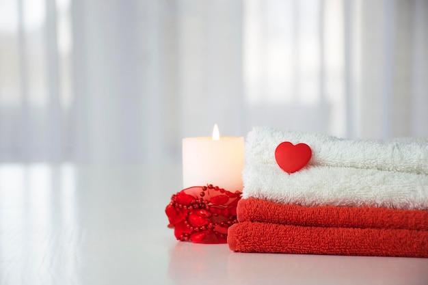 Red and white towels with heart and candle with red decor. Candle spa therapy, massage salon.