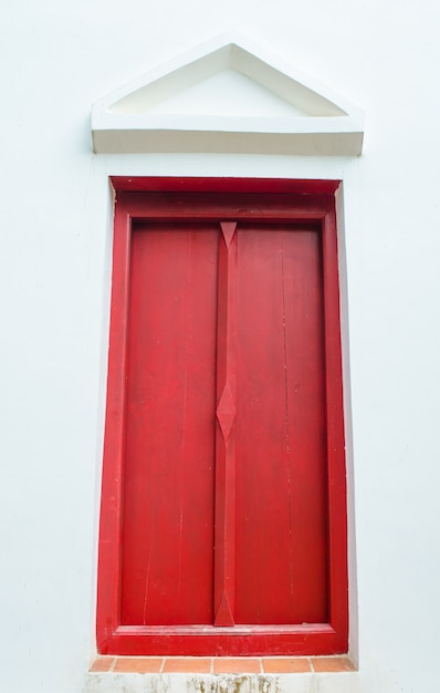 Red window on white wall with gable in temple