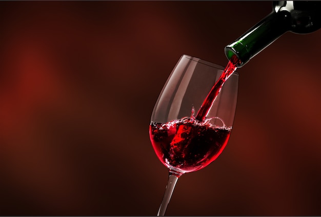 Red wine being poured in wineglass, closeup