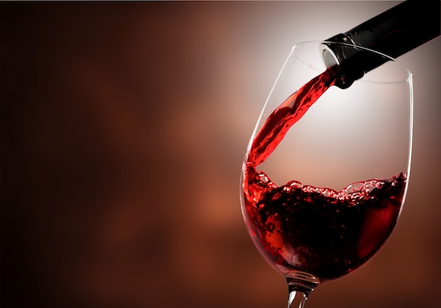 Red wine being poured in wineglass, closeup