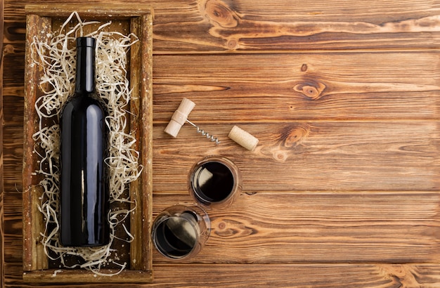 Red wine bottle corkscrew corks wine glasses on wooden table with copy space.Red Wine composition on brown wooden table. Top view.