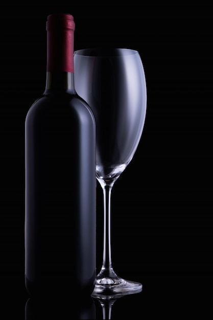 Red wine glass and a wine bottle on dark background