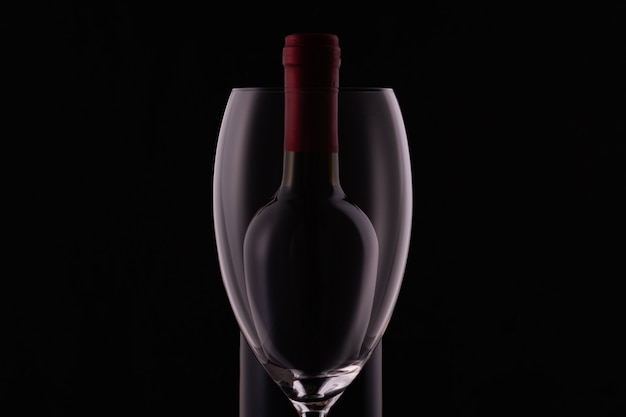 Red wine glass and a wine bottle on dark background