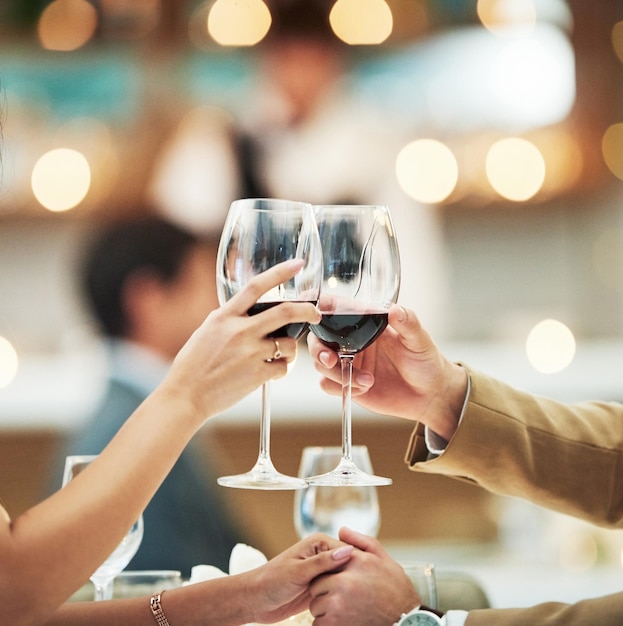 Red wine hands and date with a couple toast in a restaurant for the celebration of an anniversary Hospitality dating and romance with a man and woman drinking alcohol in cheers for fine dining