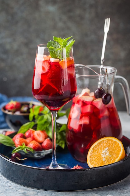 Red wine sangria or punch with fruits and ice in glasses and pincher. Homemade refreshing fruit sangria.