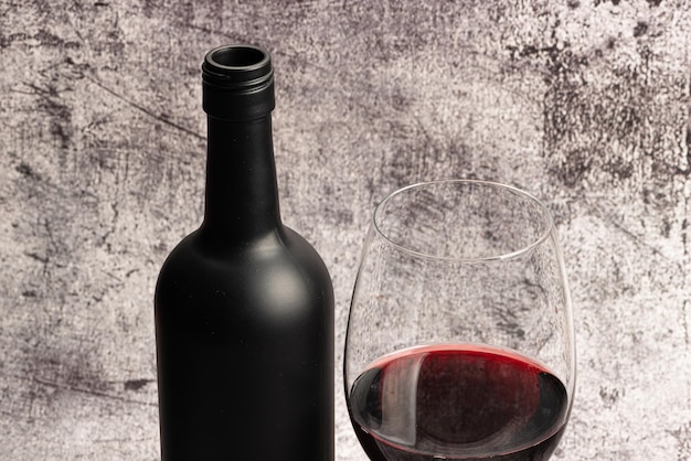 Red wine served in a crystal glass with a bottle beside it and corkscrew