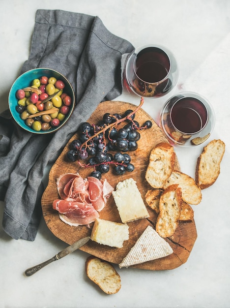 Red wine and snack set on board over grey background