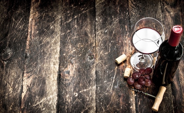 Red wine with a branch of grapes and a corkscrew