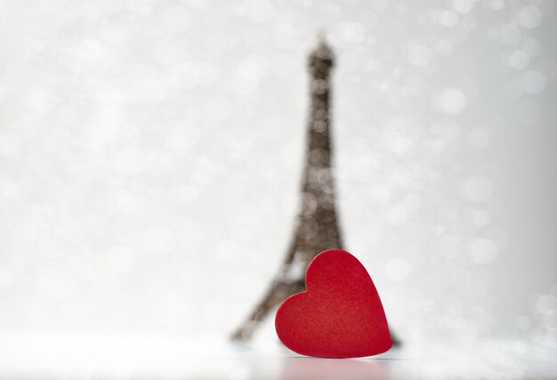 Photo red wooden heart in front of the little eiffel tower. valentine's day concept.