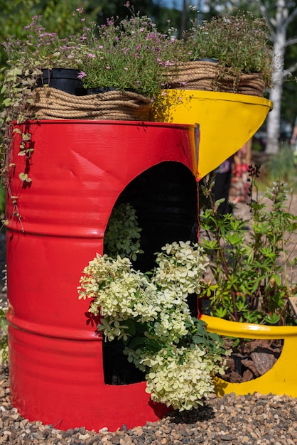 Red and yellow decorative metal barrel with flowers and grass Decorative use of an old barrel