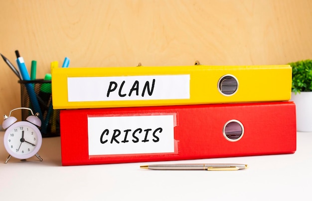 Red and yellow folders lie on the office table next to the clock and pen