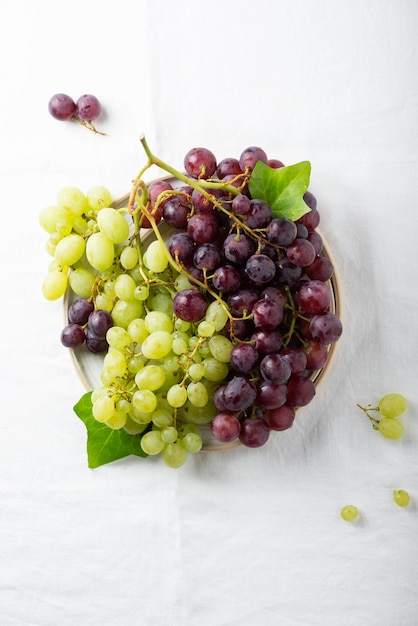 Red and yellow grape on the white linen tablecloth