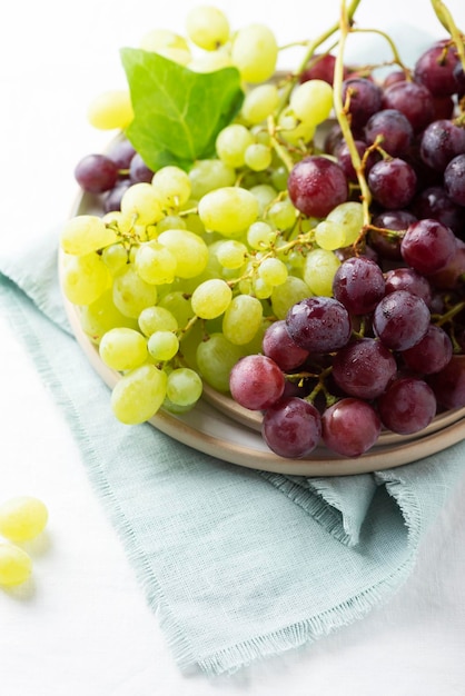 Red and yellow grape on the white linen tablecloth