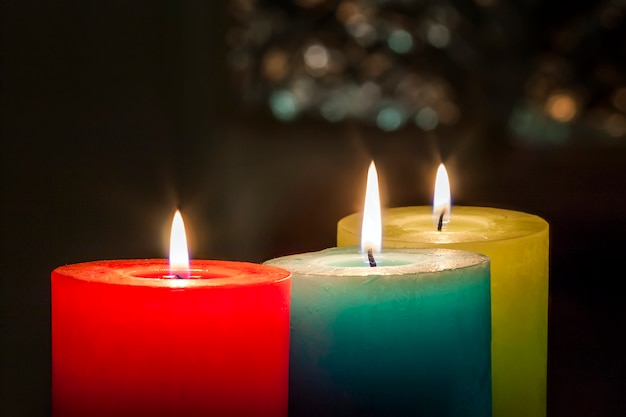 Red, yellow and green colourful candles with blurred bokeh background. Christmas and New Year copy space.