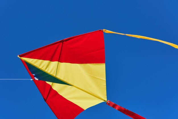 Red yellow kite fly high in blue cloudless sky Soft focus closeup