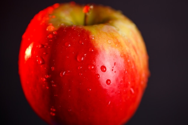 Red-yellow large apple, flooded with water on a dark background