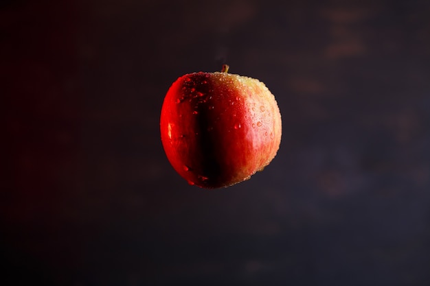 Red-yellow large apple, flooded with water on a dark background