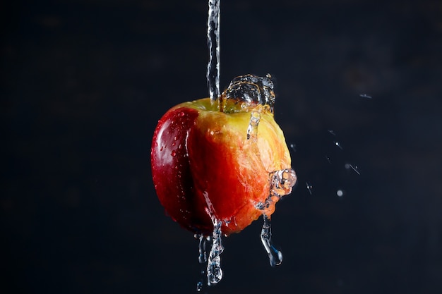 Red-yellow large apple, flooded with water on a dark background