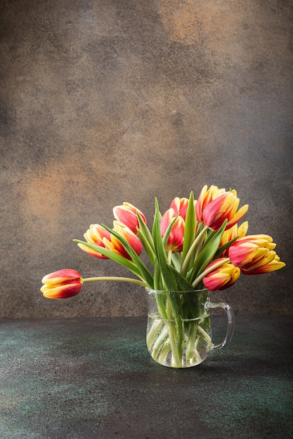 Red yellow tulips in glass vases. A gift for woman's day. Greeting card for mother's day. Celebrating Easter. Copy space