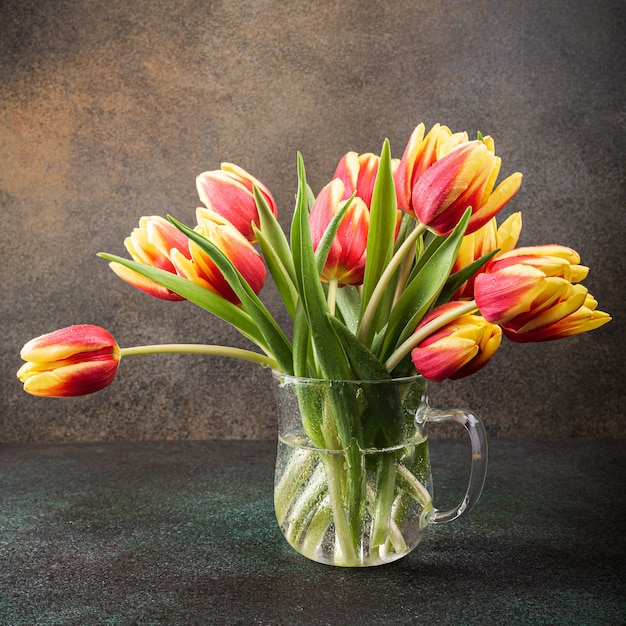 Red yellow tulips in glass vases. A gift for woman's day. Greeting card for mother's day. Celebrating Easter. Copy space