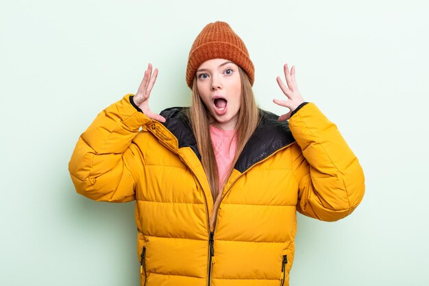 Redhair woman screaming with hands up in the air. winter concept