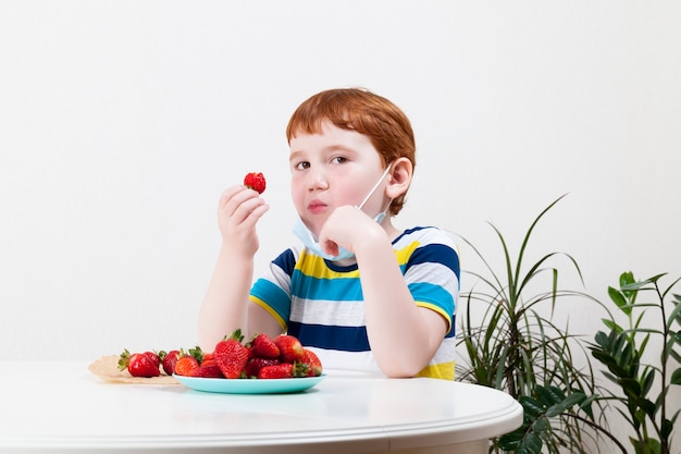 Redhaired boy eating ripe red strawberries