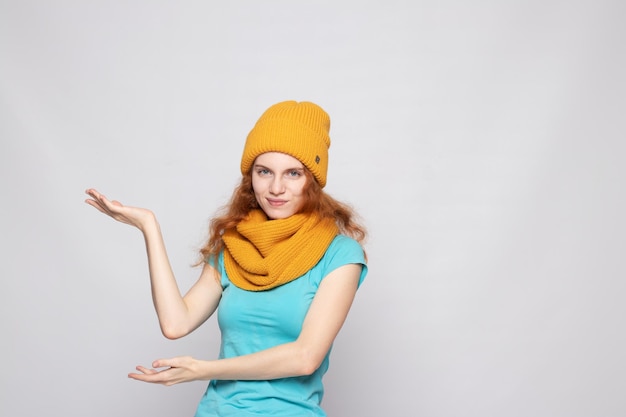 Redhaired girl in a warm hat on a light background