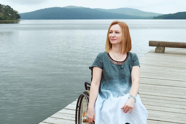 Redhaired mature woman with a disability enjoys a summer day at the seaside