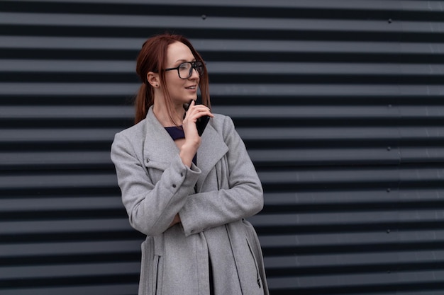 Redhaired yearold businesswoman against a gray relief wall